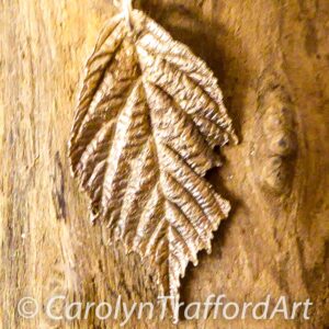 A small blackberry leaf which has been nibbled a little in pure silver